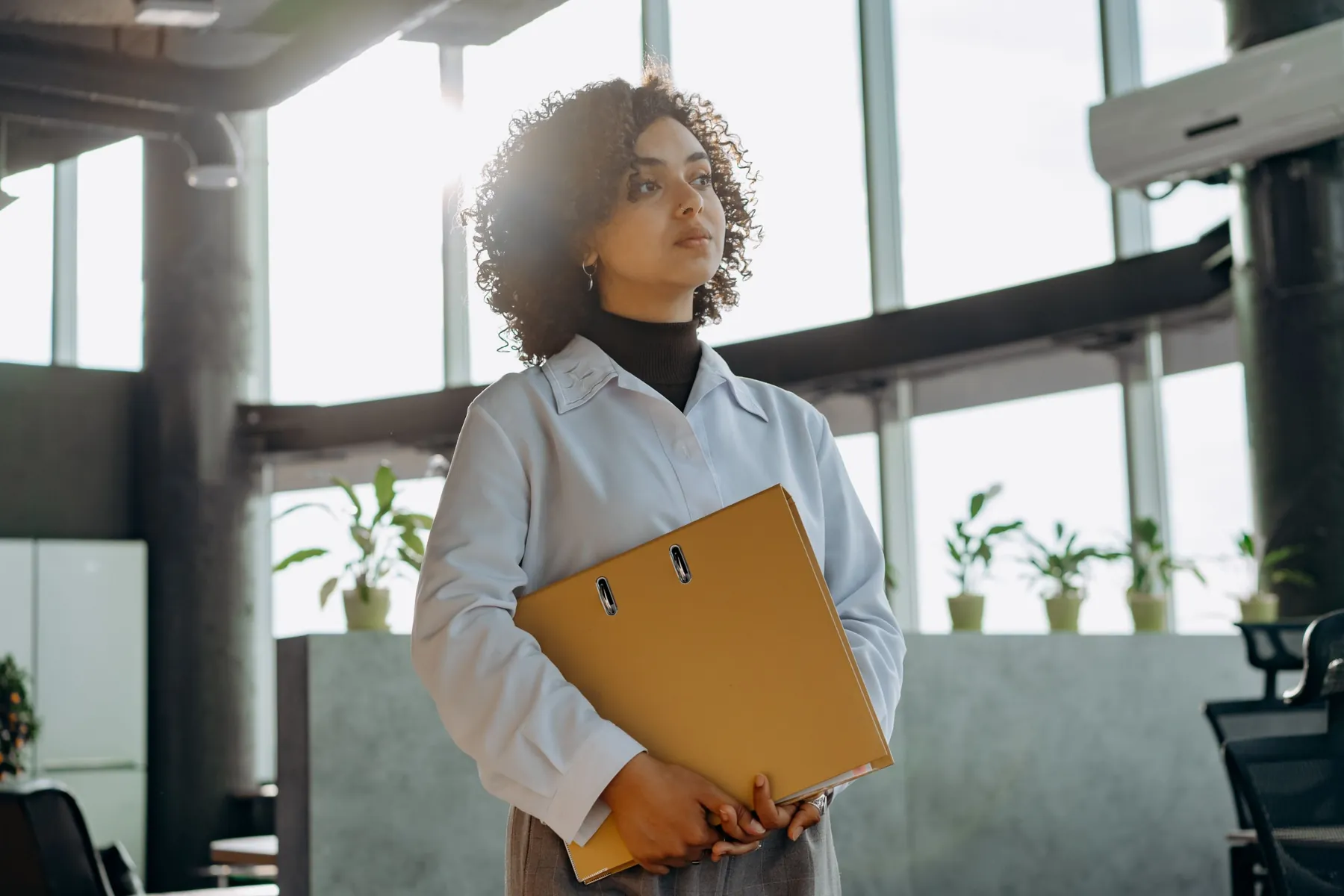 Collaboratrice tenant un classeur dans des bureaux lumineux